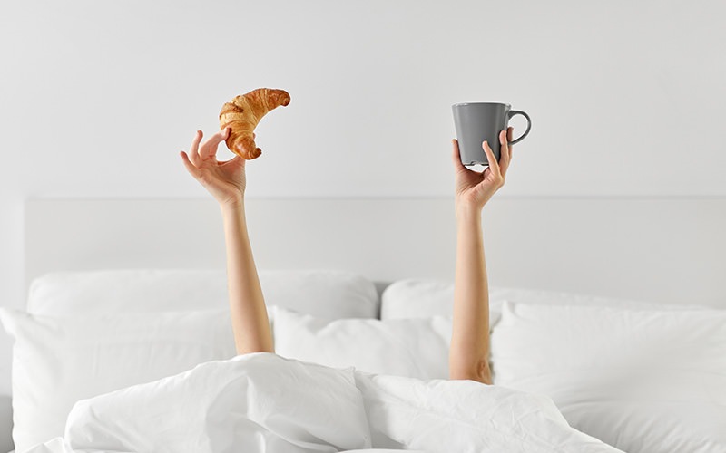 someone holding up a croissant and a cup