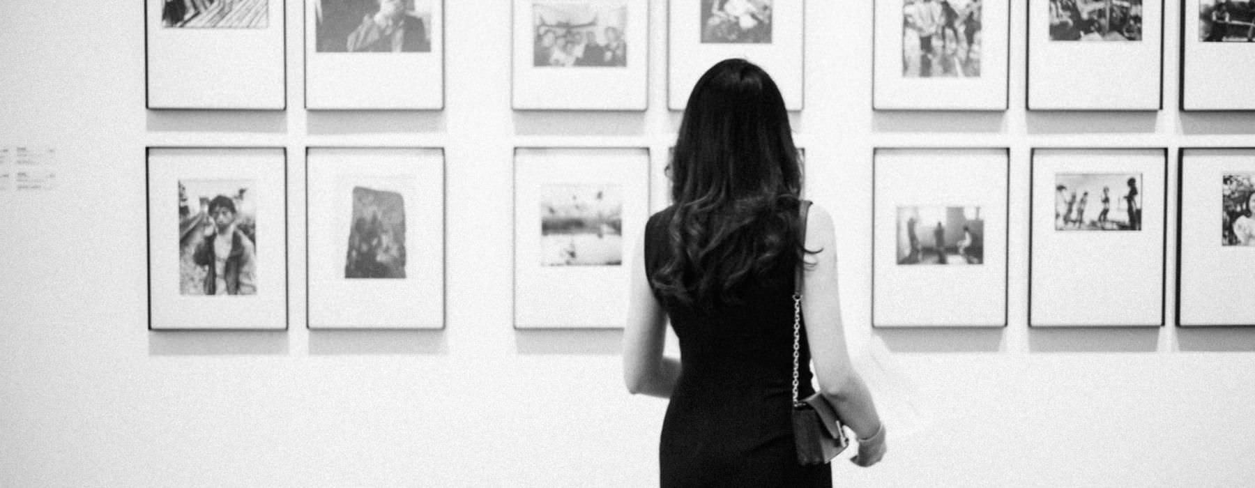 a woman looking at a wall of photographs